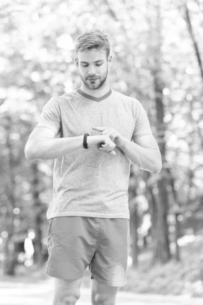 デジタルスポーツウォッチ。アスレチックマンは、手に時計でトレーニングを追跡します。屋外でのトレーニング中にスマートウォッチを使用してハンサムなアスリート。スポーツマンは、フィットネストラッキングのための時計アプリをチェック — ストック写真