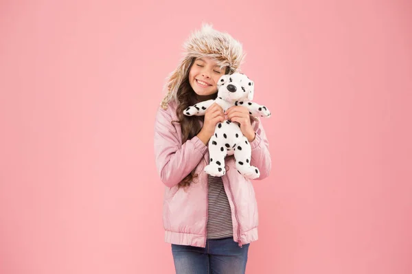 Positive emotions. Happy small smiling child play with soft dog on pink background. Happy little child hold play toy. Kindness concept. Lovely happy kid friendly dog. Charity and donation concept