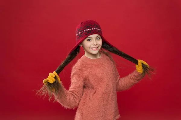 Neidisch langes Haar kommt einfach vor. Glückliche Mädchen halten lange Haare roten Hintergrund. Kleines Kinderlächeln mit langen brünetten Haaren. Krähen dicke und lange Haare. Haarpflege für den Winter — Stockfoto