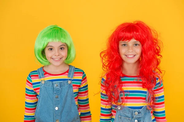 Elegante e artístico. Crianças felizes usam perucas de cabelo na moda fundo amarelo. Meninas pequenas sorriem com aparência elegante. Salão de cabeleireiro elegante. Moda e estilo — Fotografia de Stock