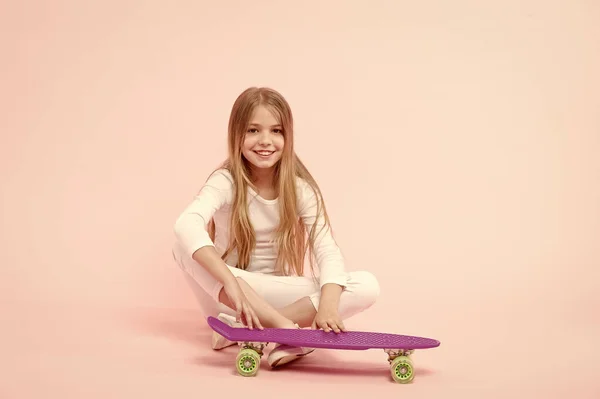 アクティブなライフスタイル。ペニーボードピンクの背景を楽しんでいる女の子。子供愛らしい子供の長い髪はペニーボードに乗って崇拝。幸せな子供時代ペニーボードに乗って、トリックを行います。女の子はスケートボードに乗るのが好き — ストック写真