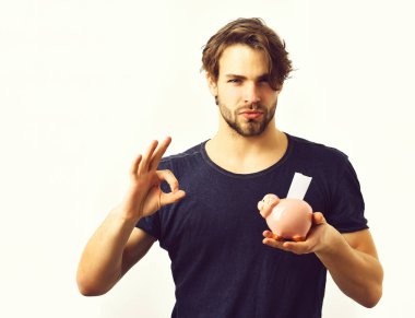 Beyaz seksi genç maço elinde pembe domuz kumbarası tutuyor.