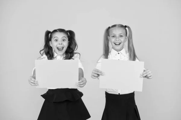 Publicidade e marketing genial. Crianças gênio feliz segurando folhas de papel em branco no fundo amarelo. Gênio meninas sorrindo com cartazes vazios. Ideia de gênio, espaço de cópia — Fotografia de Stock