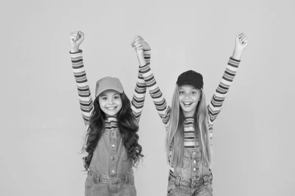 Celebrando la victoria. Chicas felices celebrando el logro en el fondo amarillo. Pequeños niños lindos celebrando y haciendo gestos ganadores. Sigue celebrando las fiestas aún no han terminado. — Foto de Stock