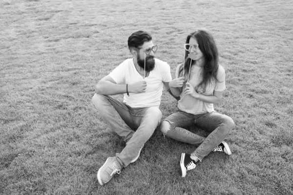 そうなるはずのカップル緑の草の上で楽しみを持っている愛のカップル。あごひげの男とセクシーな女性のカップルは、スティックにパーティーの小道具を保持しています。夏の日に一緒にリラックスする家族のカップル — ストック写真
