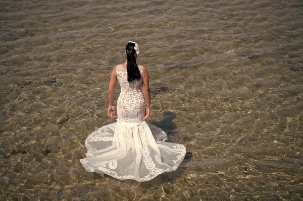 Luna di miele in località balneare. Matrimonio all'estero. Cerimonia nuziale in riva al mare. Sposa bianco abito da sposa stand in acqua di mare. Abito da sposa bagnato caldo giorno di sole. Sposa felice godere di vacanze estive oceano sfondo — Foto Stock