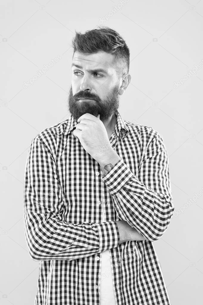 Bearded for your pleasure. Bearded man on yellow background. Bearded hipster touching his unshaven chin. Brutal caucasian guy with mustache and beard on bearded face