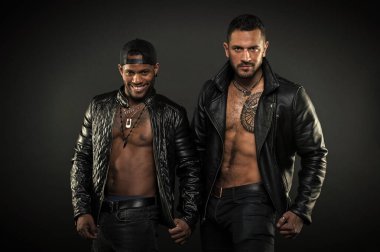 Çıplak torsolar ile vücut geliştiriciler. Geniş gülümseme şapkası olan Afrika neşeli adam. Acımasız beyaz adam kıllı göğüs dövme ile. Motorcu deri mont kaslı vücut, erkeklik kavramı üzerinde