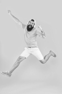 Mutluluk şarkısı. Sakallı adam sarı arka planda mutlulukla atlıyor. Mutlu hipster modern kulaklıklar müzik dinleme keyfini çıkarın. Mutluluk frekansı. Mutluluk ve olumlu düşünme için müzik