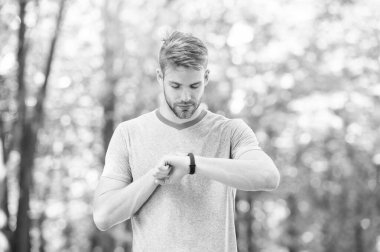 Kalori sayıyorum. Bilek bandı aleti. Atlet kontrol fitness izci doğa arka plan. Kıllı atlet pedometre gadget ilerleme sonucu bakar. Akıllı saat gadget ile sporcu eğitimi