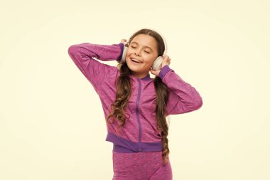 Ne harika bir duygu. Atletik küçük kız beyaz izole rahatlatıcı. Sevimli kız çocuk müzik dinliyor. Kulaklık takan küçük kız uygun. Aktif kız kulaklıkla müzik çalmanın keyfini çıkarın