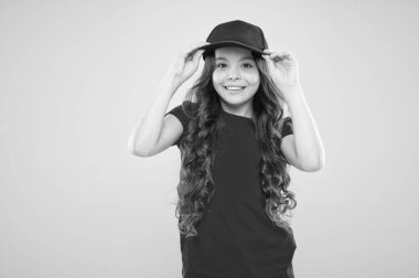 Sevimli çocuk şapkası takıyor ya da şapkası takıyor. Beyzbol şapkası takan küçük bir kız. Yaz güneşi koruma şapkası. Uzun kıvırcık saçlı bir kız şapka takıyor. Sokak tarzı aksesuarları olmalı. Modern moda. Çocuk modası