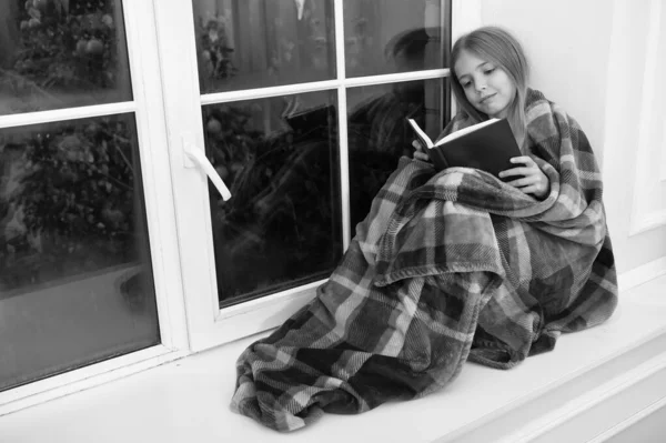 Merry Christmas. Little girl enjoy reading Christmas story. Little child read book on Christmas eve. Little reader wrapped in plaid sit on window sill. Childrens picture book. Magic xmas spirit — Stock Photo, Image