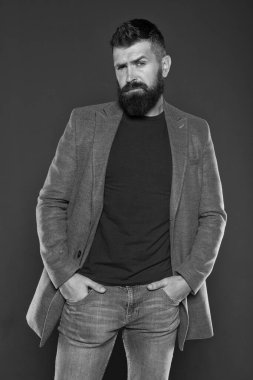 Sakallı ve barbar. Sakallı adam gri arka planda kollarını cebinde tutuyor. Sıradan tarzda sakallı hippi. Vahşi traşsız adam sakallı yüzüne bıyık ve sakal takıyor.