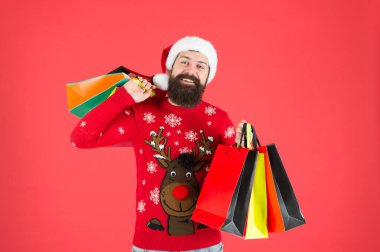 Organize bir müşteri. Kompülsif alıcı. Perakende. Neredeyse Noel 'de. Aileye hediyeler. Sakallı hippi alışveriş çantası taşır. Noel Baba hediye aldı. Noel hediyeleri. Geyikli yılbaşı kazaklı adam.