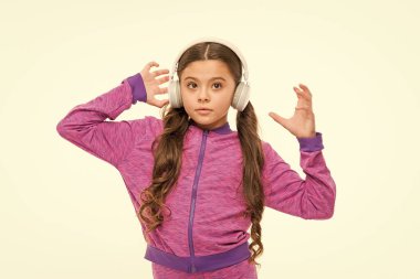 Dinlenme zamanı. Aktif kız kulaklıkla müzik çalmanın keyfini çıkarın. Atletik küçük kız beyaz izole rahatlatıcı. Sevimli kız çocuk müzik dinliyor. Kulaklık takan küçük kız uygun