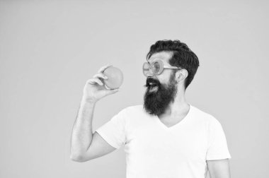 En iyi portakallı atıştırmalık. Mutlu adam sarı arka planda atıştırmalık molası veriyor. Hipster sağlıklı organik atıştırmaya bakıyor. Size enerji veren atıştırmalık, kopyalama alanı