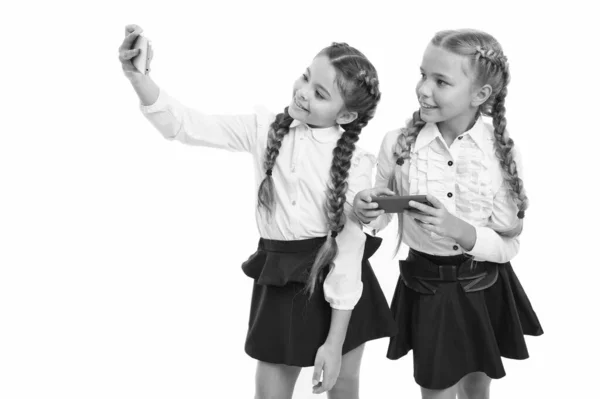 Het voeden van uw blog cultuur. Kleine schoolkinderen maken selfie voor nieuwe blog geïsoleerd op wit. Kleine bloggers houden het schoolleven blog. Leuke meiden die blog Foto's maken met smartphones, kopieer ruimte — Stockfoto