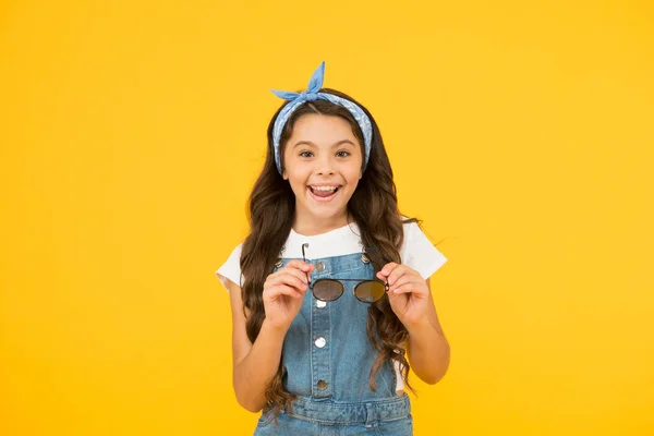 Modo de férias ligado. Tendência de verão. Pequena fashionista. Menina de moda infantil bonito. Conceito de férias de verão. Menina longo cabelo encaracolado óculos de sol amarrado lenço de cabeça. Boutique de roupas de crianças. Acessórios de verão — Fotografia de Stock