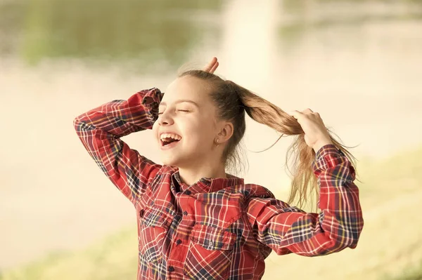 Be happy and smile. Happy little girl enjoy doing her hair on summer day. Adorable small child with long blond hair and happy smile. Happy international childrens day