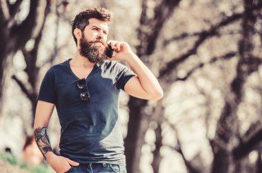 hipster adam akıllı telefon tutun. konuşma ve tartışma. cep telefonu ile acımasız işadamı. sakallı adam cep telefonuyla konuşuyor. Sakallı olgun hipster. iş konuşmak. parkta yürüyüş