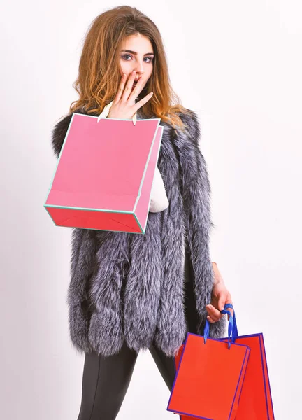 Shopping concept. Woman shopping luxury boutique. Lady hold shopping bags in hands. Fashionista buy fashionable clothes in shop. Girl makeup face long hairstyle wear fur vest white background — Stock Photo, Image