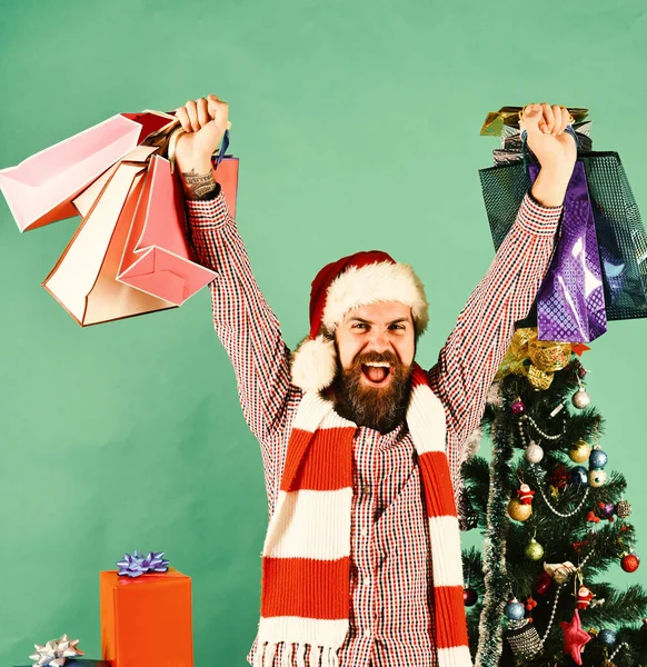 Weihnachtsmann mit bunten Päckchen neben geschmücktem Tannenbaum. — Stockfoto