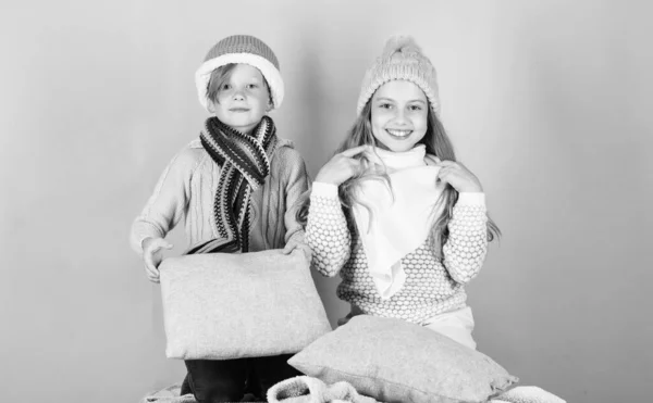 Niños y niñas se calientan con almohadas y sombreros. Manténgase caliente y cómodo. Calienta tu ropa de invierno con accesorios lindos y acogedores. Los hermanos usan sombreros cálidos de invierno sobre fondo rosa — Foto de Stock
