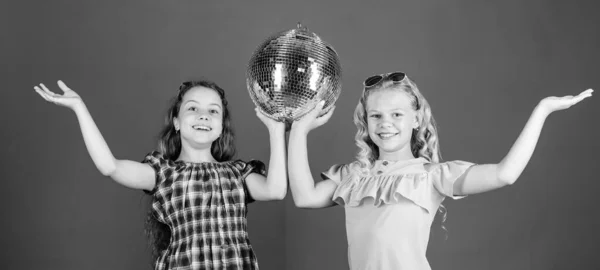Entertainment concept. Sisters friends with disco ball. Lets start party. Cheerful kids hold disco ball. Disco dances. Retro music. Mirrors reflecting lights disco atmosphere. Holiday celebration