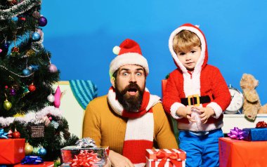 Noel Baba ve küçük yardımcısı Noel ağacının yanındaki hediye kutularının arasında