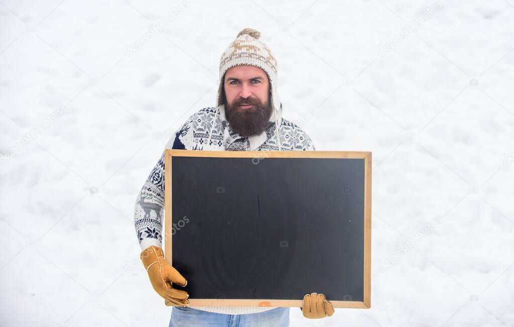feel cold. winter season. Christmas sales. ski and sledge. bearded man in warm clothes. Happy new year. man advertising board. Copy space. happy hipster with blackboard. winter holiday. Party here