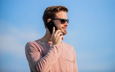 Önemli bir cep telefonu sohbeti. Adam cep telefonu. İrtibatı koparmayalım. Mobil çağrı konsepti. Başvuru ve internet. Hippi güneş gözlüğü takıyor cep telefonuyla gökyüzü arka planı tutuyor. Hippi akıllı telefon görüşmesi.