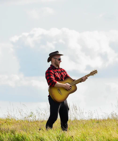 Verhogend vermaak. country muziek liedje. sexy man met gitaar in geblokt shirt. westelijk kamperen en wandelen. cowboy man met akoestische gitarist. hippe mode. gelukkig en vrij — Stockfoto