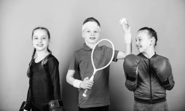 Amici pronti per l'allenamento sportivo. Il bambino potrebbe eccellere in sport completamente diversi. Fratelli sportivi. Ragazze bambini con attrezzature sportive di boxe e giocatore di tennis ragazzo. Modi per aiutare i bambini a trovare lo sport di cui godono — Foto Stock