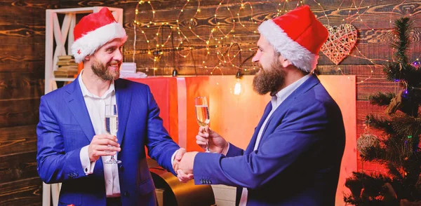 New year corporate party. Business people drink champagne at party. Party with champagne. Colleagues celebrate new year. Men formal suits and santa hats hold champagne glasses. Cheers concept