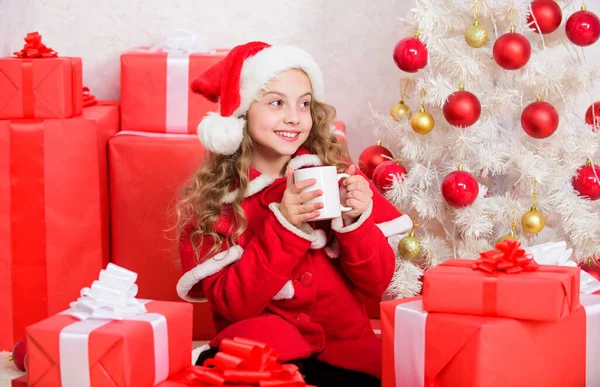 Dziewczyna małe słodkie dziecko trzymać kubek z gorącym napojem podczas świętowania Bożego Narodzenia. Gorące kakao w Wigilię. Ulubiony napój kakaowy. Kapelusz Mikołaja lubi napój kakaowy. Idealny sposób na rozgrzanie sezonu wakacyjnego — Zdjęcie stockowe