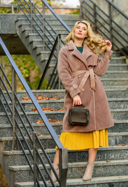 Girl warm coat stand urban stairs background. Create fall outfit to feel comfortable and pretty. Autumn outfit. Woman wear stylish outfit and carry purse. Outerwear of modern warm and stylish eco fur — Stock Photo, Image