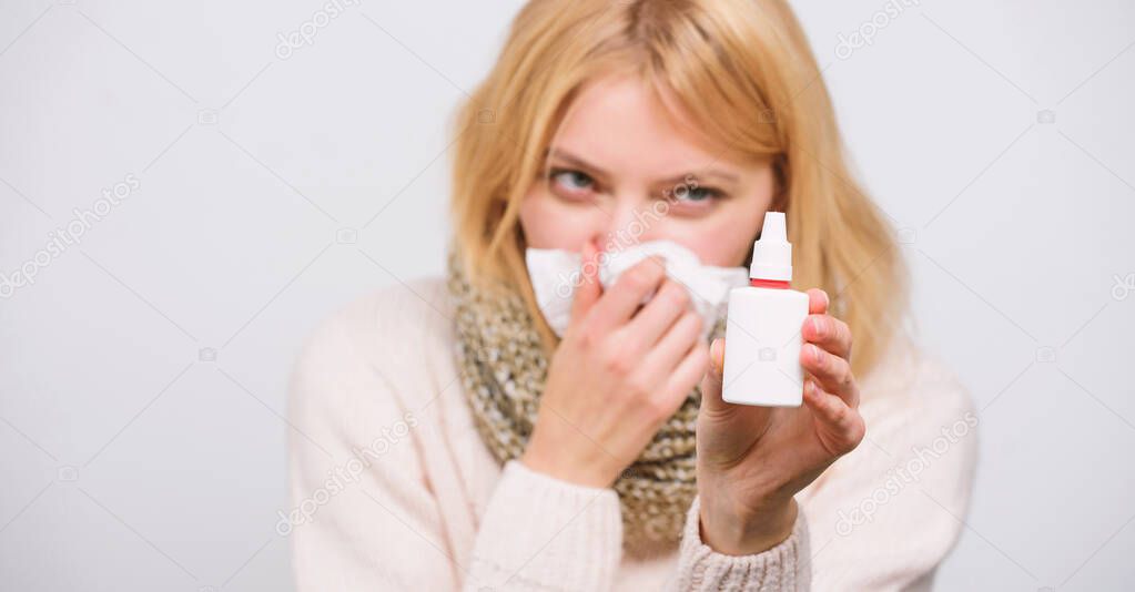 Finding relief just a spray away. Sick woman spraying medication into nose. Ill girl with runny nose using nasal spray. Cute woman nursing nasal cold or allergy. Treating cold or allergic rhinitis