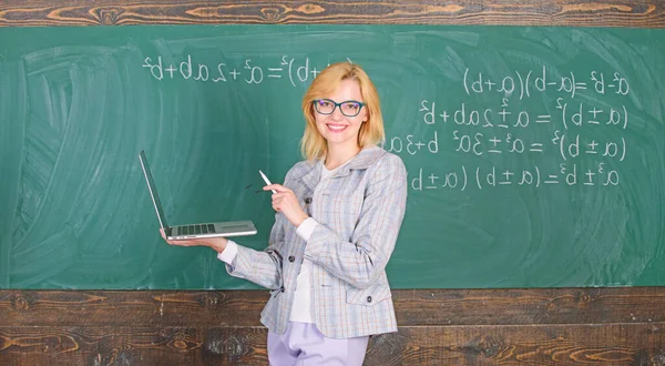Educador senhora alegre com laptop moderno surf internet chalkboard fundo. Educação é divertido. Professora mulher usar óculos detém laptop de surf internet. Conceito de tecnologias digitais — Fotografia de Stock