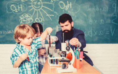 Sınıfta test tüpleri olan öğretmen ve öğrenciler. İlginç okul dersleri. Okul eğitimi. Okul kimya sıyrık deneyi. Okul kulübü. Çocuğa kimyayı açıklamak. Büyüleyici kimyasal reaksiyon