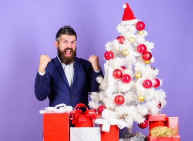 Noel hediyeleri ve dekorasyonlar. Harika bir ofis noel partisi nasıl düzenlenir. Kutlamaya hazırım. Noel hazırlığı ve kutlaması. Sakallı hippi adam Noel ağacının yanında resmi takım elbise giyer.