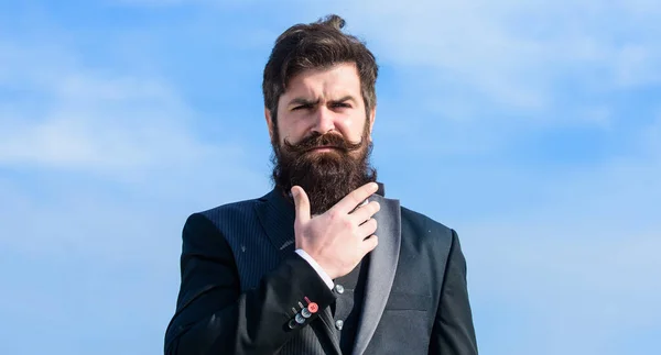 Barbe longue de style vintage. Soins de la barbe et de la moustache. Tendance de la mode barbe. Investissez dans l'apparence élégante. Faites pousser la barbe épaisse rapidement. Homme barbu hipster porter costume formel bleu ciel fond — Photo