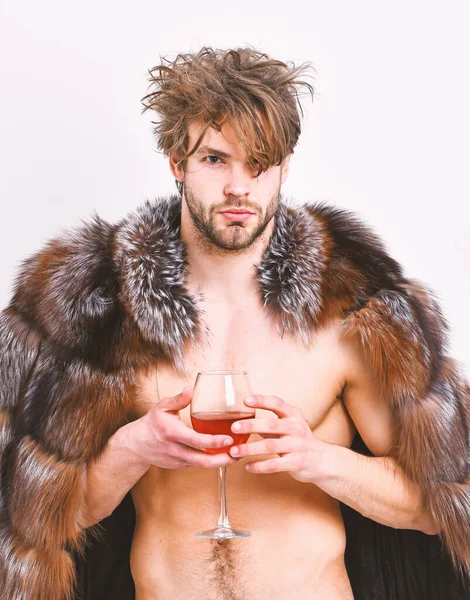 Sexy sonolento rico macho tousled vinho bebida de cabelo isolado em branco. Saúde e bem-estar. Riqueza e conceito de luxo. Guy atraente rico posando casaco de pele no corpo nu. Atleta rico desfrutar de sua vida — Fotografia de Stock