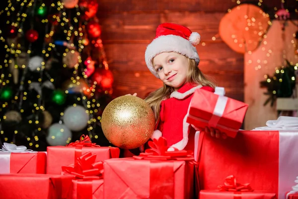 Для тебе. Приваблива дитина-санта дарує подарунки. Маленька дитина святкує Різдво і Новий рік. Маленька дитина в червоному капелюсі в день боксу. Мила дівчинка з різдвяними ящиками з Санти. — стокове фото