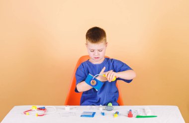 Tıbbi muayene. Tıp eğitimi. Oyun oyna. Çocuk sevimli çocuk gelecek doktor kariyer. Sağlıklı bir hayat. Sağlık. Çocuk küçük doktor steteskop ve tıbbi aletlerle masaya otursun. Tıp kavramı