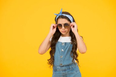 Sıcak ve güneşli. Neşeli küçük kız sarı duvar. Retro çocuk uzun saçı. Küçük çocuk klasik güneş gözlüğü. Tatil modu başladı. Küçük moda düşkünü. Çocuk giyim mağazası. Retro kız. Yaz moda konsepti