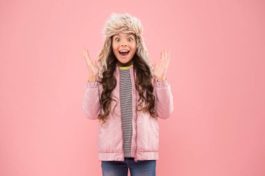Bu ne sürpriz. Çocuk modası. Kız hipster gibi görünüyor. Mutlu çocuk pembe arka planı. Kürk şapka aksesuarı. Küçük kız kış kulaklığı. Sonbahar tarzı. Çocukluk aktivitesi. Soğuk mevsim için sıcak kıyafetler