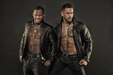 Modeller çıplak torsolar, moda kavramı deri ceket giyiyor. Altı paket ve dövmeli sandıkları motorcularla. Afrika adam beyaz bir gülümseme ile. Küçük kıl beyaz adamla. Bodybuilders seksi organları ile