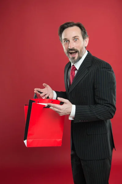 Frumoasă achiziţie. Reducere şocantă. Omul de afaceri matur deține hârtie sac cadou fundal roșu. Conceptul de cumpărături. Cadou de Crăciun. Sărbători fericite. Omul fericit sărbătorește noul an. Cadou Ziua Îndrăgostiților — Fotografie, imagine de stoc