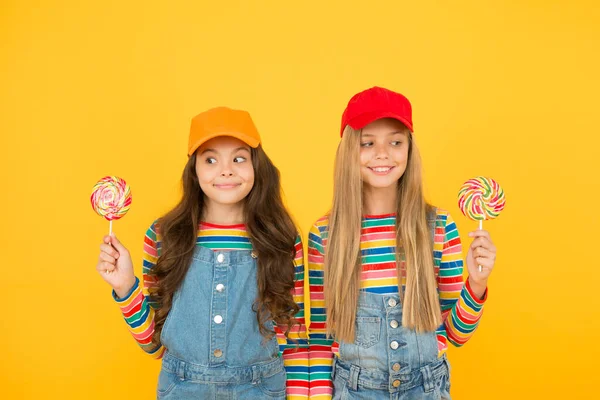 Glücklicher Kindertag. niedlichen Schwestern Lutscher Bonbons. fröhliche Kinder haben Partyspaß. Schulfreunde genießen die Feiertage. Süßwarenladen-Konzept. Süßes Leben. Kinderglück. positiv und freundlich — Stockfoto